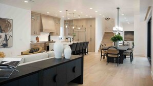A modern kitchen with wooden cabinets, a central island, and pendant lighting. - Designer Digs 9 Bedroom Home (St. George)