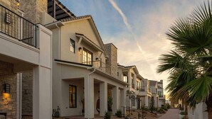 A modern multi-story residential building with a stone facade, balconies, and a pathway leading to the entrance. - Designer Digs 9 Bedroom Home (St. George)