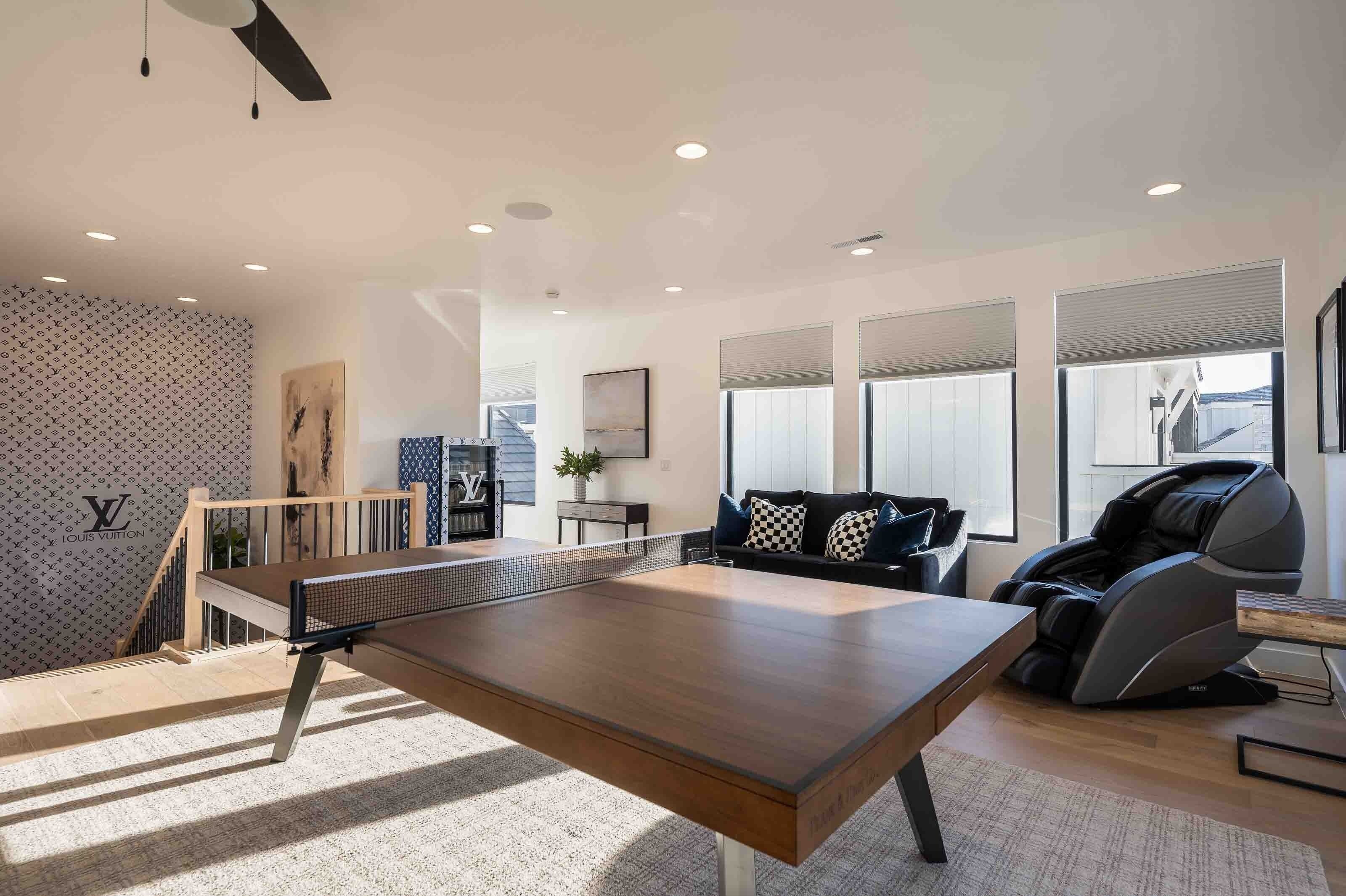 Una sala de estar moderna con una mesa de ping pong, una silla de masaje y una escalera.