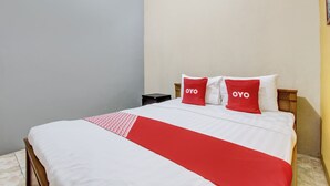 A neatly made bed with a red and white bedspread and two red pillows with the word "OYO" on them. - Hotel O Griya Pius Syariah Malioboro (Yogyakarta)