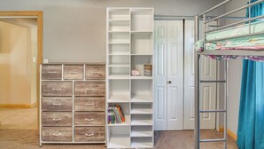 Ein Zimmer mit einem Etagenbett, einem weißen Regalschrank und einer Holzkommode.