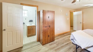 Ein Schlafzimmer mit Bett, Kleiderschrank, Deckenventilator und angrenzendem Badezimmer.