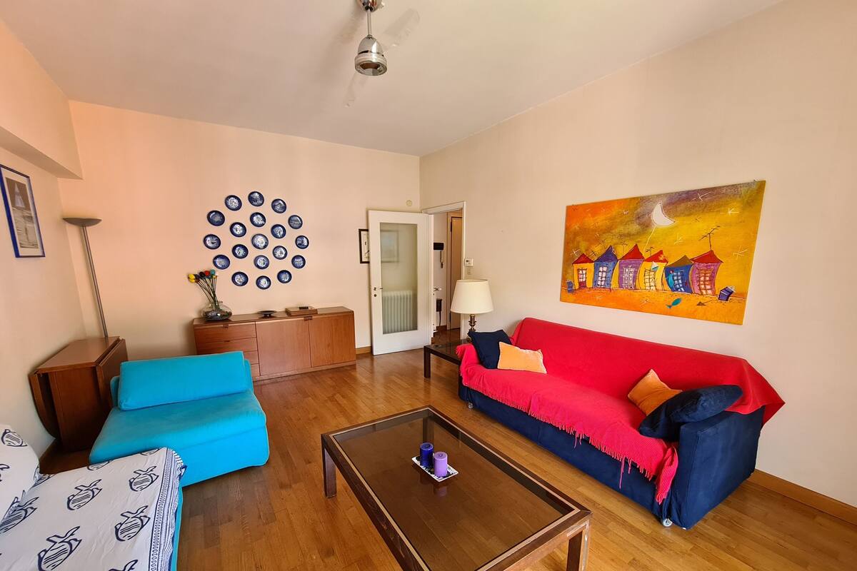 A living room with a blue sofa, a red sofa, a coffee table, and a wall with blue plates.