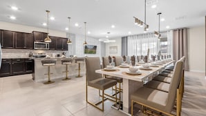 A modern kitchen with dark cabinets, a central island with bar stools, and pendant lighting.