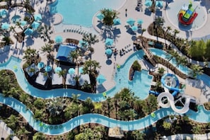 A large pool with a water slide, lounge chairs, and umbrellas. - 3508 Lavender Windsor · New Luxury Home | Windsor Island by Disney w/Pool (Davenport)