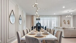 Un comedor con una mesa larga dispuesta para una comida, rodeado de sillas.