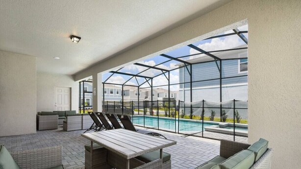 Un patio cubierto con piscina, mobiliario de mimbre y vistas del entorno.