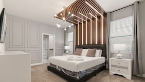 Une chambre à coucher moderne avec un grand lit, une table de chevet, une commode et un luminaire au plafond.