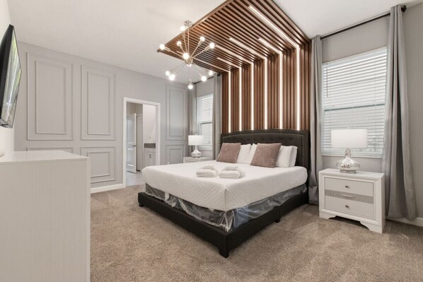 A modern bedroom with a large bed, a nightstand, a dresser, and a ceiling light fixture.