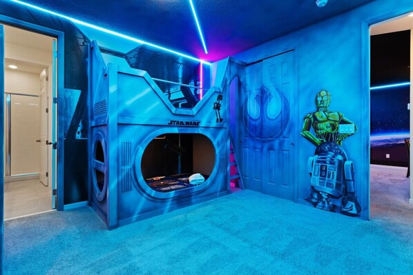 A Star Wars-themed room with a circular window, a Star Wars logo, and a R2-D2 mural.