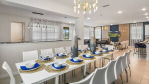 A modern dining area with white tables, blue and gold placemats, and a chandelier. - Disney| Solara Resort Pool & Spa (Kissimmee)