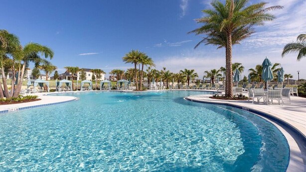 A large, clear swimming pool with palm trees and lounge chairs around it. - Disney| Solara Resort Pool & Spa (Kissimmee)