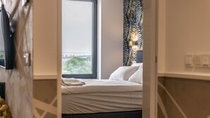 Une chambre à coucher avec un lit, une fenêtre et une lampe fixée au mur.