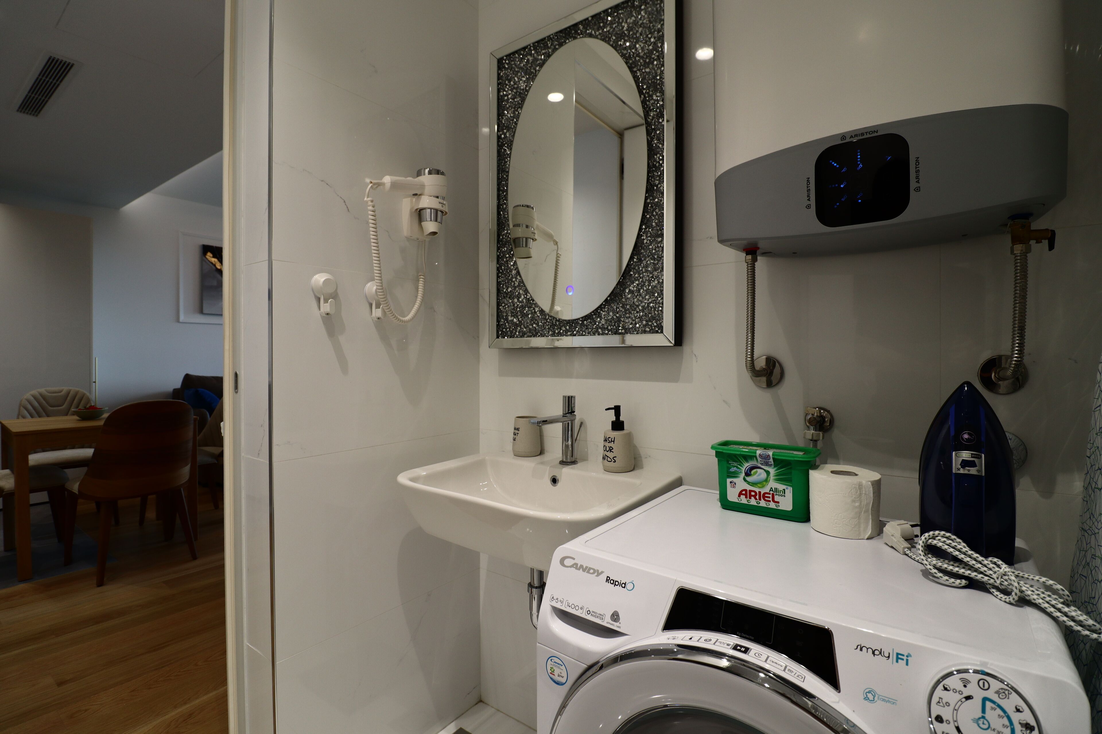 Un bagno con lavatrice, lavandino, specchio e asciugacapelli.