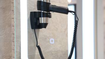 A hairdryer mounted on a wall with a cord.