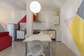 Uma cozinha compacta com área de refeições, um sofá vermelho e uma luminária pendente moderna.