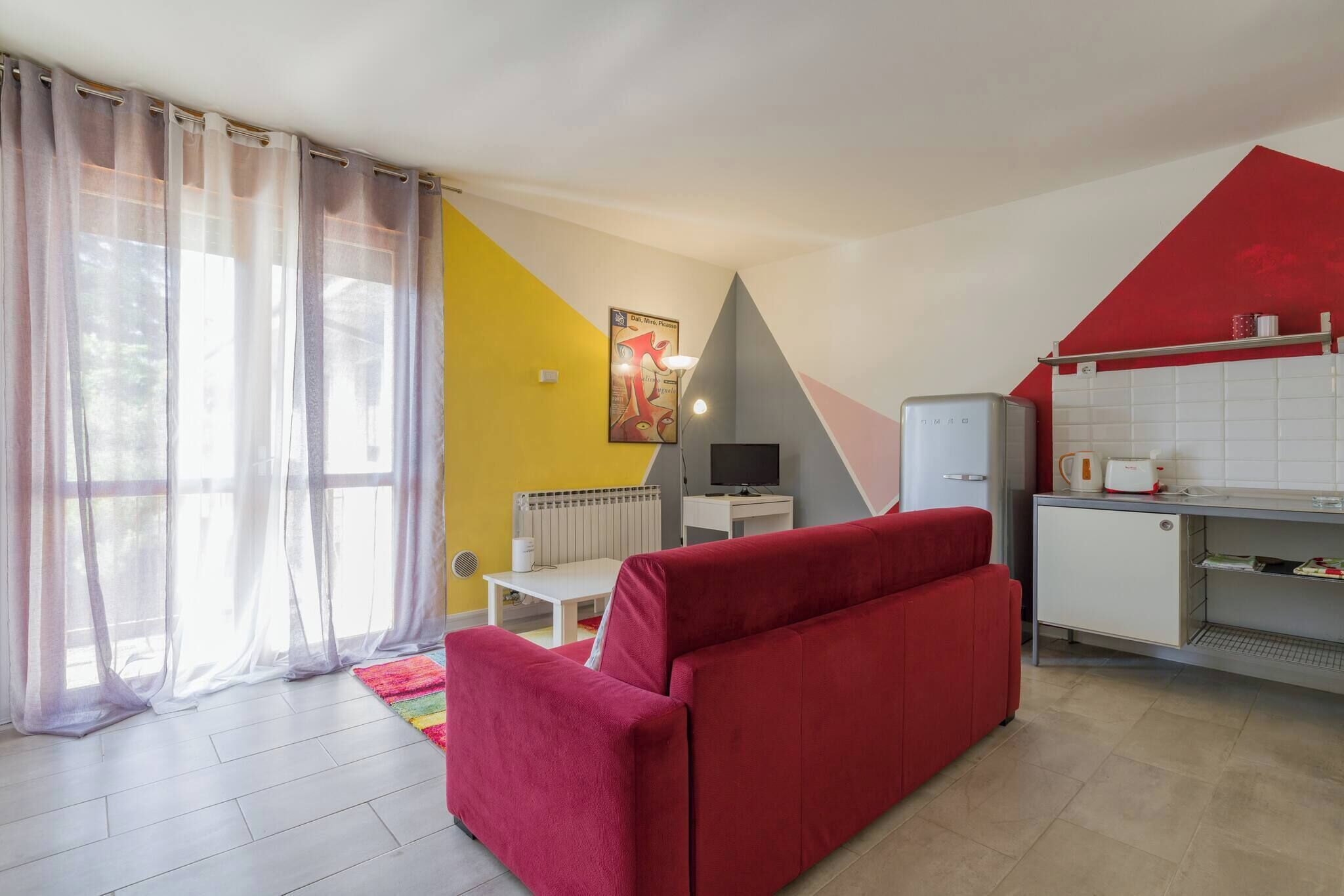 Una cocina moderna con un sofá rojo, televisión y refrigerador.