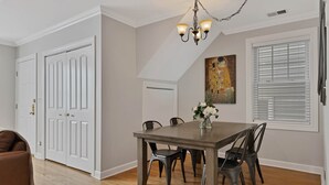 Un coin repas avec une table et des chaises en bois, un lustre et un tableau au mur.