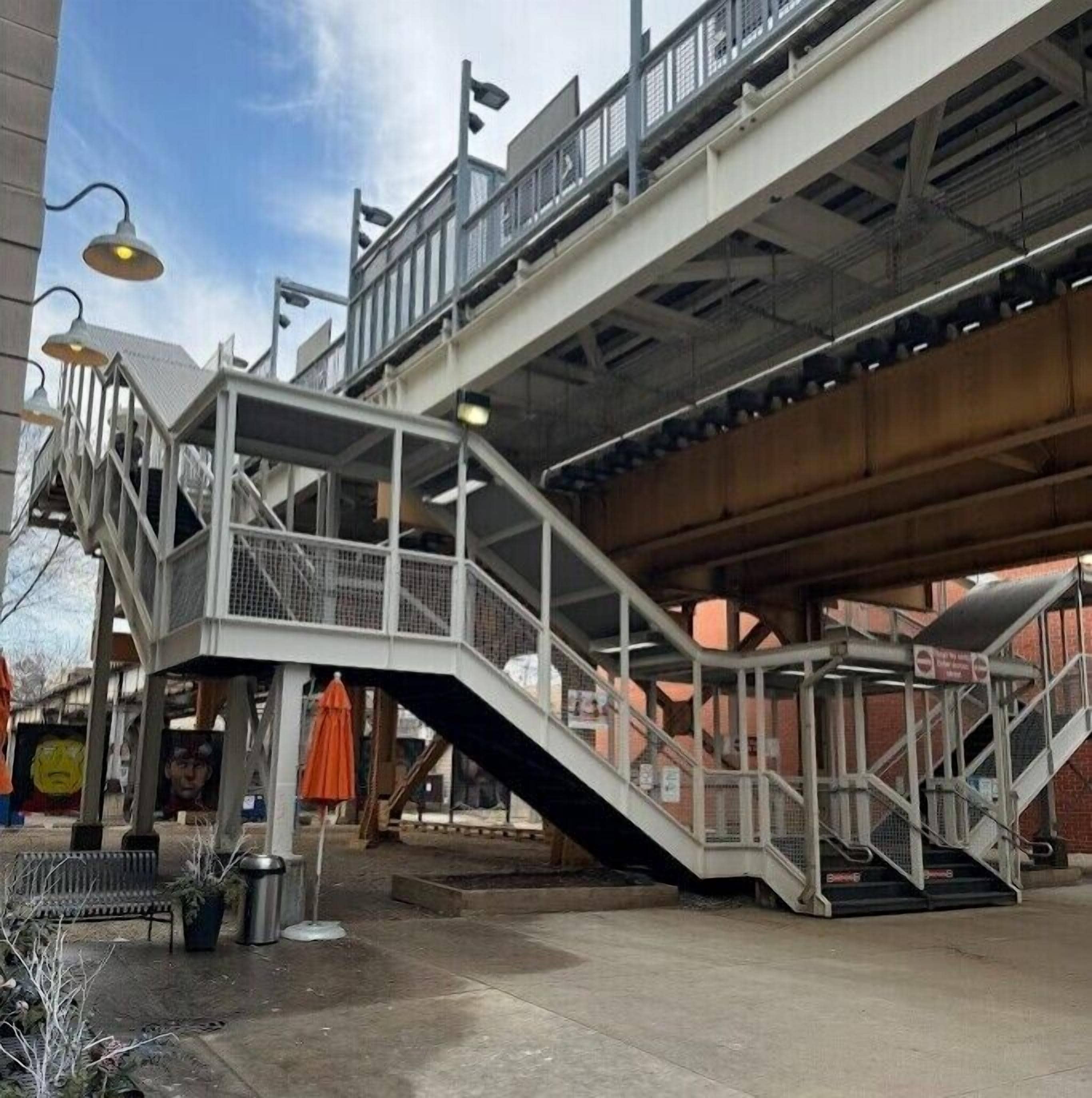 A pedestrian bridge with metal railings and a staircase leading up to a building.
