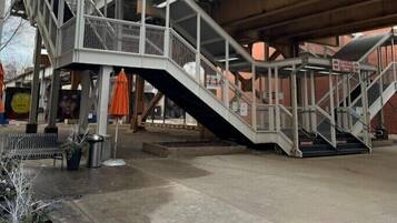 A pedestrian bridge with metal railings and a staircase leading up to a building.