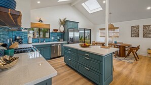 A spacious kitchen with teal cabinetry, a large island, and a skylight.