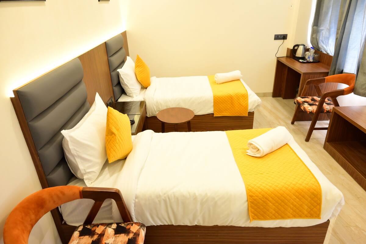A hotel room with two beds, a desk, and a chair.