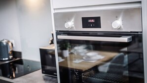 Een moderne keuken met een digitale klok, roestvrijstalen apparatuur en een koffiezetapparaat.