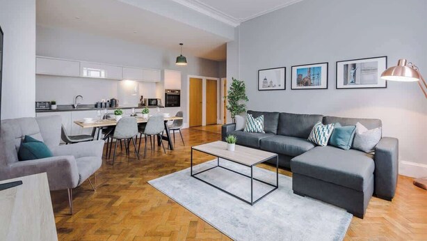 Een moderne woonkamer met een bank, salontafel en een eethoek.