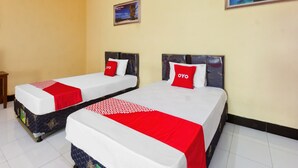 Two single beds with red and white bedding, a small table, and a framed picture on the wall. - Capital O 93391 Golden Manggis Hotel Near SMKN 1 Lingsar (Batu Kumbung)