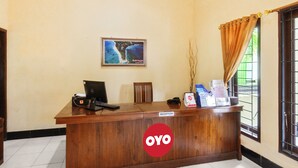 A reception desk with a sign reading "OYO" and a framed picture of a coastal scene on the wall. - Capital O 93391 Golden Manggis Hotel Near SMKN 1 Lingsar (Batu Kumbung)