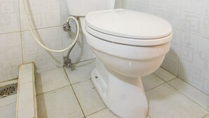 A bathroom with a toilet, a shower, and tiled walls. - Capital O 93391 Golden Manggis Hotel Near SMKN 1 Lingsar (Batu Kumbung)