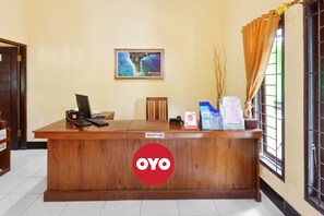 A reception desk with a sign reading "RECEPTION" and a logo "OYO". - Capital O 93391 Golden Manggis Hotel Near SMKN 1 Lingsar (Batu Kumbung)