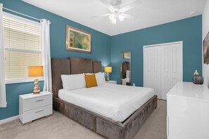 Cozy retreat with a large bed, nightstand, dresser, and ceiling fan.