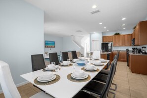 Enjoy meals in this dining area with a long table, black chairs, and modern decor.