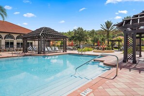 Relax by the pool surrounded by lush greenery and a gazebo.