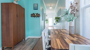 Una cocina con encimera de madera, sillas blancas y un mueble de madera.