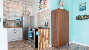 Una cocina con armarios blancos, un mueble de madera, un refrigerador de acero inoxidable y una encimera de madera.