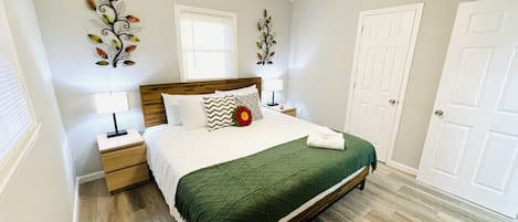 Un dormitorio con cama, mesitas de noche, ventilador de techo y una puerta.