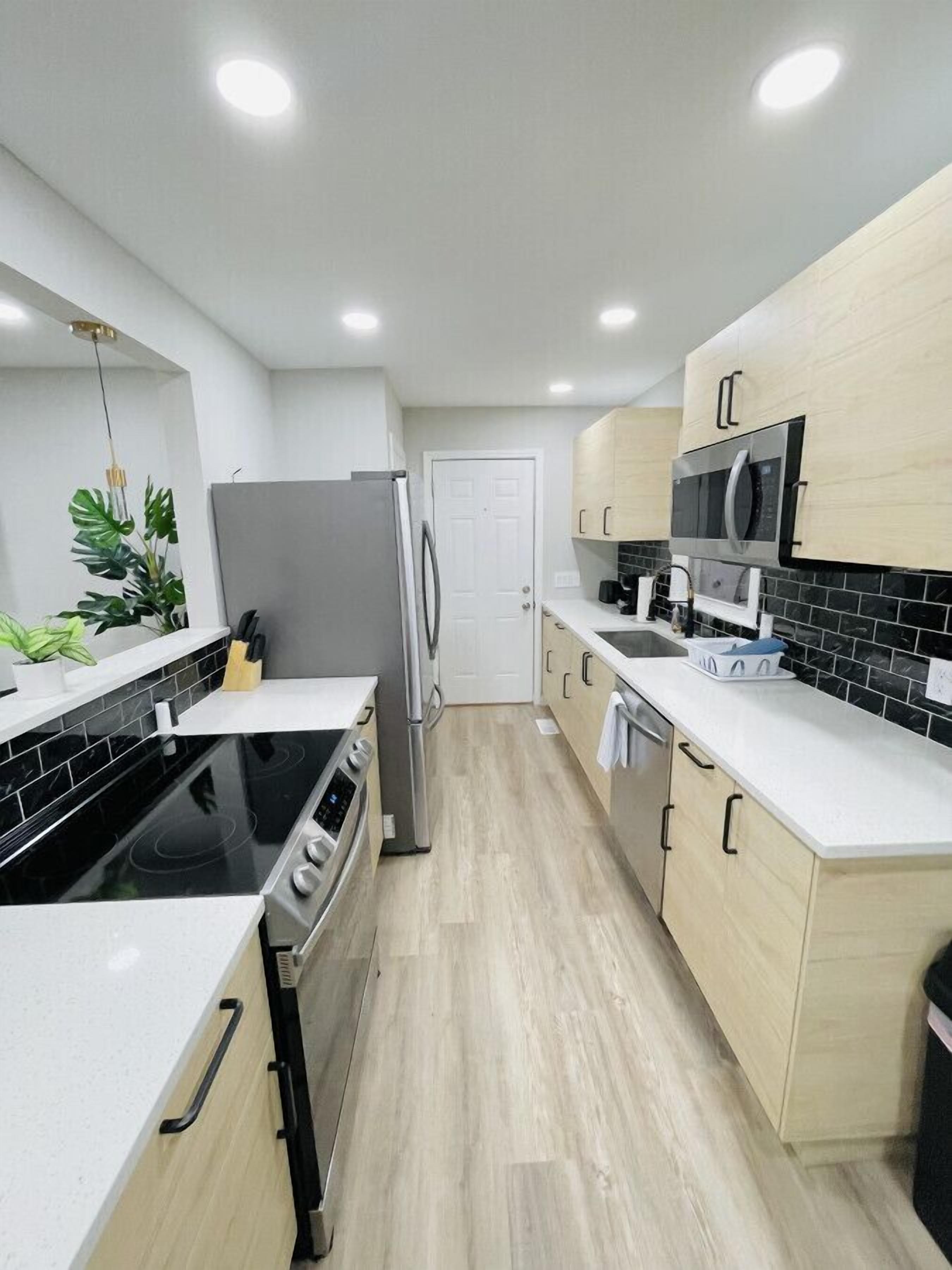 A modern kitchen with a black stovetop, stainless steel refrigerator, and white cabinetry.