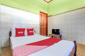 Une chambre d’hôtel avec un lit, un téléviseur posé sur une petite table et une porte.