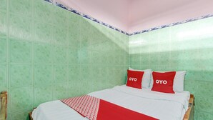 Une chambre avec un lit, deux oreillers ornés du mot « OYO », et des murs à motifs verts.