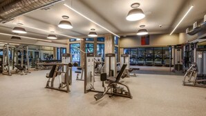 Uma academia moderna com diversos equipamentos de exercício, amplas janelas e um interior limpo e bem iluminado.