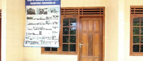 A wooden door with a glass panel, a poster with photographs, and four wooden stools.