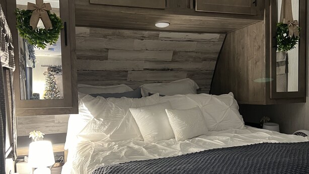 A bedroom with a wooden headboard, white bedding, and a dark blue throw blanket. - Cozy camper in Clemson Hills.  5 minutes from Clemson University.  Pet friendly! (Seneca)