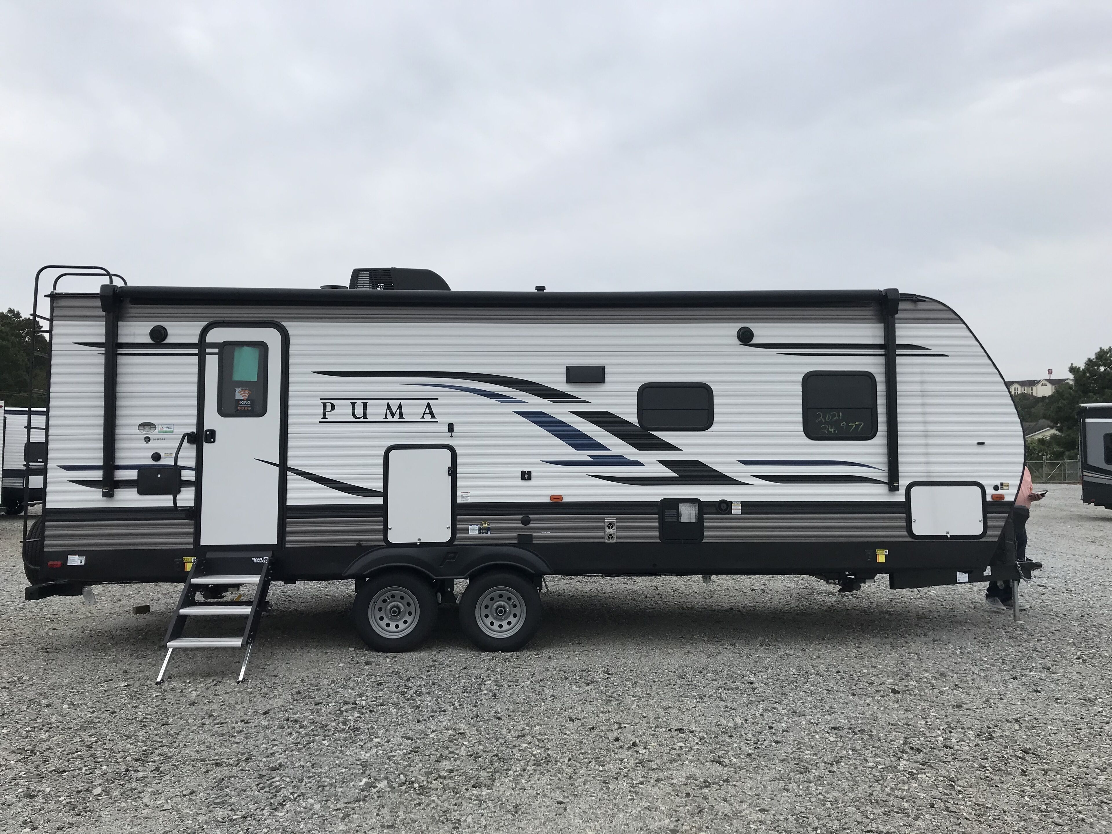 A PUMA RV with a ladder, a small enclosed area, and a window.