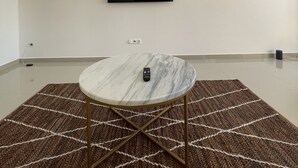 A modern room with a marble table, a remote control, and a flat-screen TV mounted on the wall. - Biss Apartments Mindelo - T1 Madalena nearby the beach (Mindelo)