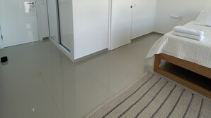 A modern bedroom with a bed, a sliding door closet, and a large window. - Biss Apartments Mindelo - T1 Madalena nearby the beach (Mindelo)