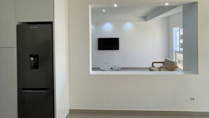 A modern kitchen with a built-in refrigerator and a flat-screen TV mounted on the wall. - Biss Apartments Mindelo - T1 Madalena nearby the beach (Mindelo)