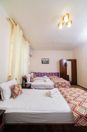 A hotel room with two beds, a wardrobe, a mirror, and a ceiling light fixture. - Caravan Boutique Inn (Khiva)