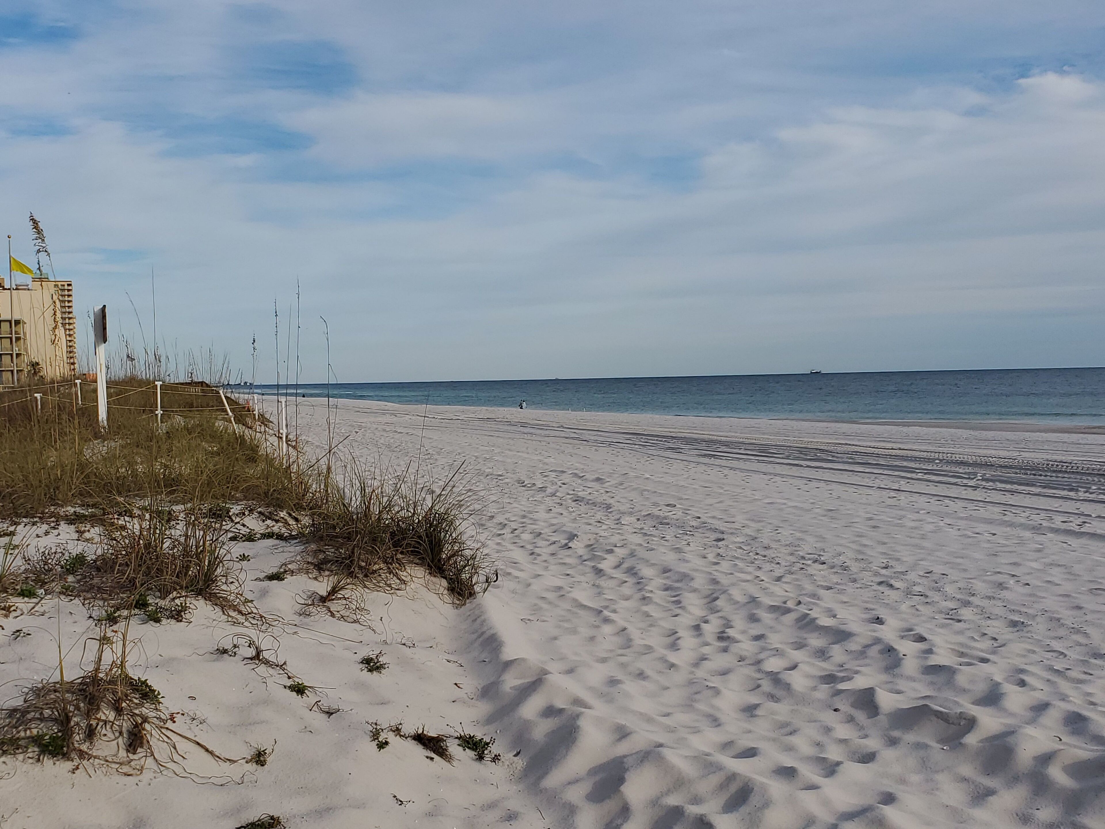 A sandy beach with a clear sky and calm sea.